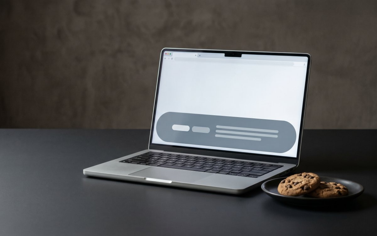 Тарелка с печеньем рядом с ноутбуком, на экране страница с плашкой о cookie и двумя кнопками